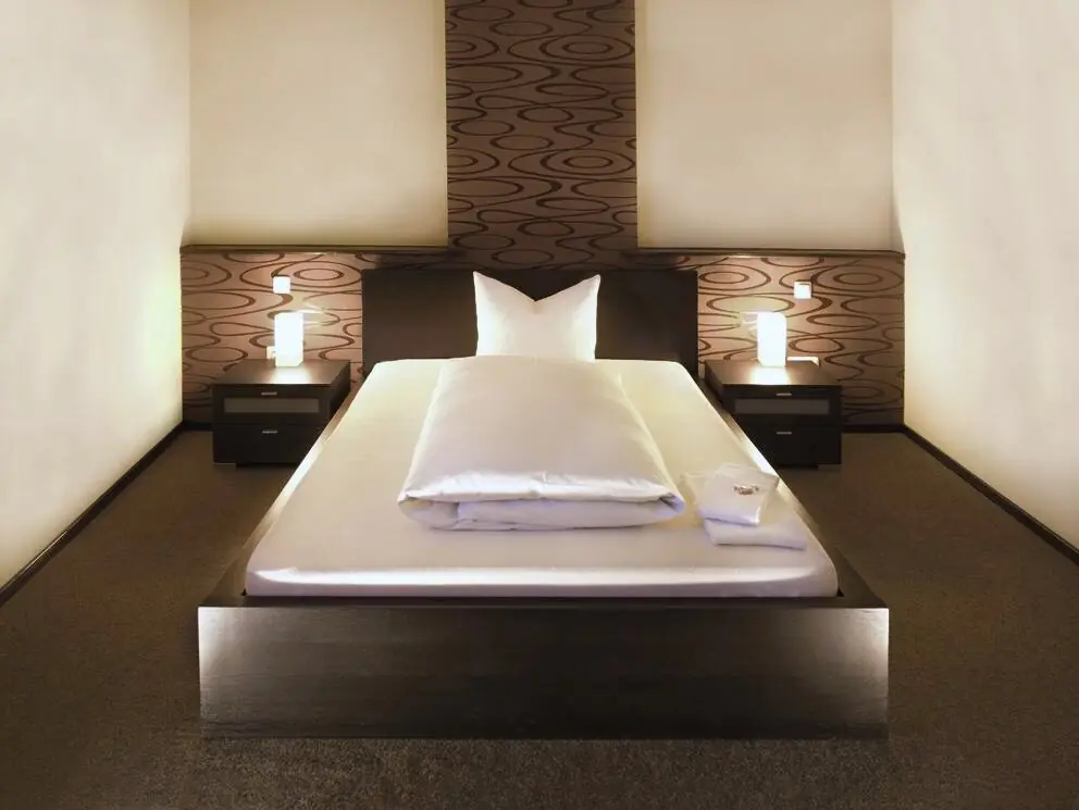 Hotelzimmer mit großem Bett und warmem Licht im Hotel Goldener Falke Augsburg